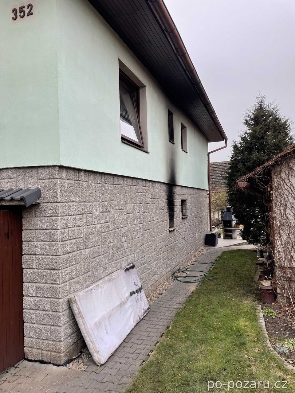 Zděný dům se sazemi nad okenním otvorem po požáru stropu.